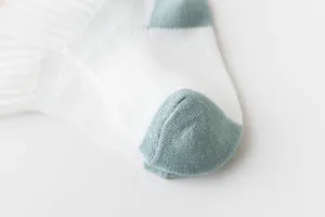 Close-up detail of breathable baby mesh socks, white with blue-green heel and toe.