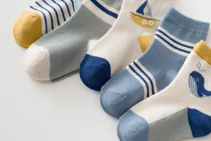 Gros plan de chaussettes en coton pour enfants avec motifs de baleine et bateau mignons.