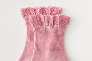 Detailed view of pink cotton baby socks featuring soft ribbed texture and elegant ruffled lace cuffs.