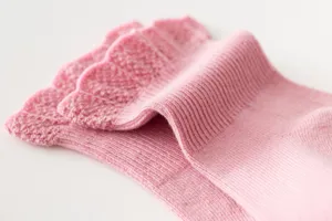 Detailed view of cute pink knit cotton socks for baby kids with delicate ruffle cuff.