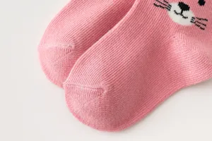 Primo piano di calzini in maglia rosa per neonati con grazioso motivo a gatto.