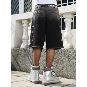 Dettaglio dei pantaloncini in denim nero slavato con ricamo floreale rosso e orlo vivo.