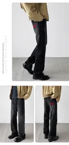 Detail view of men's black washed vintage loose denim pants with red wing patch embroidery.