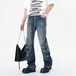 Detail view of mens blue washed distressed stacked flare jeans featuring wave pleated design.