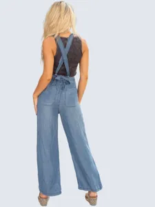 Back detail of lightweight denim jumpsuit featuring cross straps and back waist bow design.