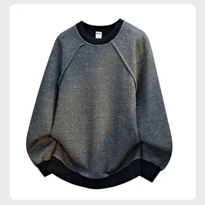 Detailed shot of the textured grey crewneck knit sweater with black ribbed cuffs and hem.