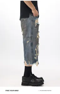 Vista dettagliata dei bermuda jeans da uomo con effetto usato e strappi sfrangiati alla moda.