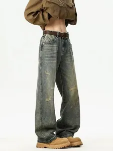 Detailed view of men's distressed baggy straight jeans with vintage wash and ripped details.