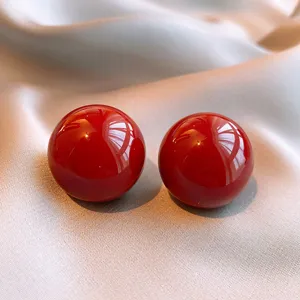 Glänzende rote kugelförmige Ohrstecker, elegantes Herbst-Winter-Design, minimalistischer Schmuck.