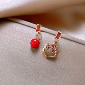 Exquisite asymmetrical red bead and geometric crystal drop earring detail, retro style.