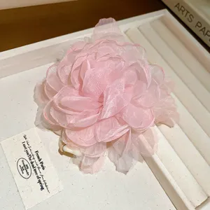 Close-up detail van een roze mesh bloem haaraccessoire, elegant gelaagd ontwerp.