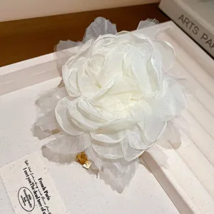Gedetailleerde close-up van een witte, gelaagde mesh bloem haarring, elegant en modieus.