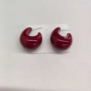 Retro dark red glossy curved hoop earrings detail shot, stylish autumn winter jewelry accessory.