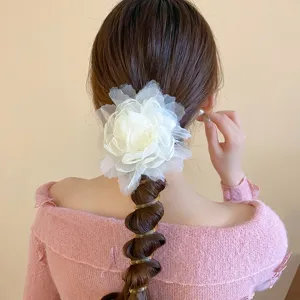 Gedetailleerd overzicht van een witte mesh bloem haaraccessoire met spiraal haarelastiek.