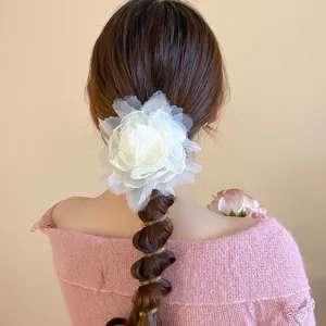 Detailopname van de elegante tule bloem haaraccessoire met spiraalvormig haarelastiek.