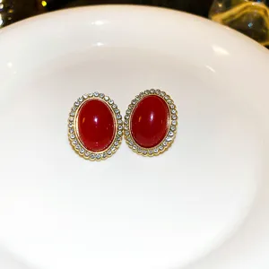 Detail shot of vintage anchor red oval rhinestone earrings in gold-tone setting on plate.