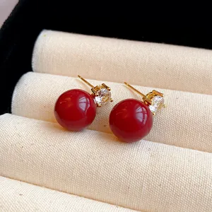 Dunkelrote kugelförmige Ohrstecker mit funkelnden Zirkonakzenten, eleganter Modeschmuck.