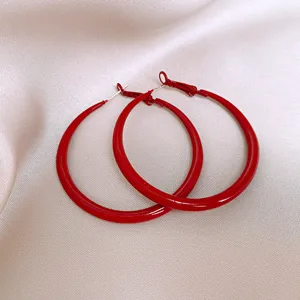Rote Creolen Detailaufnahme, minimalistisches Design, glänzendes Finish, eleganter Schmuck.