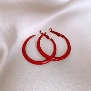Detaillierte Nahaufnahme leuchtend roter Creolen, stilvolles minimalistisches Accessoire.
