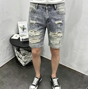 Detailed view of men's distressed denim shorts featuring ripped details and paint splatters.