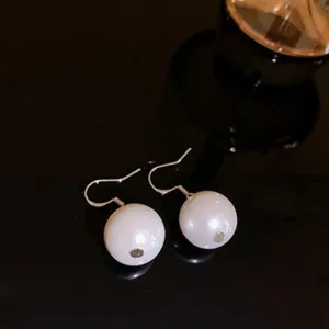 Elegant white pearl hook earrings detail shot, featuring a classic polished silver wire design.