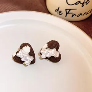 Detailed view of brown white corduroy heart shaped earrings with cute pearl bear design for autumn winter.