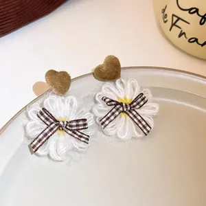 Close-up detail of cute fabric daisy earrings featuring brown heart top and chic plaid bow.