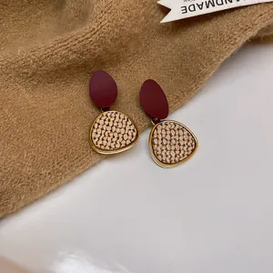 Chic geometric drop earrings featuring maroon oval tops and textured beige lower pieces.