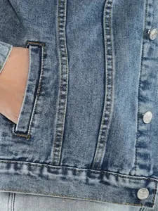 Nahaufnahme Detail der blauen Jeansjacke Tasche mit robusten Nähten und Metallknopf.