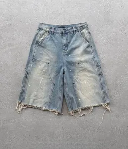 Vue détaillée de short en denim élimé avec éclaboussures de peinture et bord brut ample.