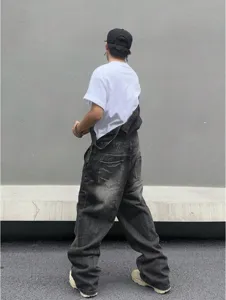 Detail view of men casual baggy washed black denim overalls, streetwear style fit.
