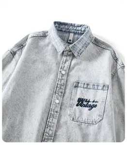 Vista dettagliata di una camicia di jeans azzurro slavato con colletto a quadri e tasca.