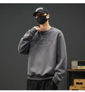 Nahaufnahme Detail eines dunkelgrauen Fleece-Crewneck-Sweatshirts mit geprägtem Brusttext.