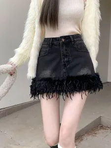 Gros plan détaillé de la mini-jupe en jean noir pour femme avec un ourlet à franges duveteuses.