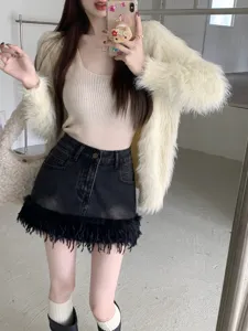 Gros plan détaillé de la mini-jupe en jean noir à franges, assortie d'un cardigan duveteux chic.