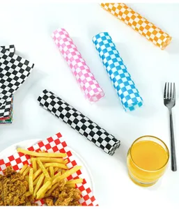 Detailansicht von kariertem Pergamentpapier als Unterlage für Brathähnchen und Pommes