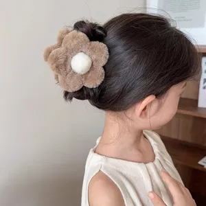 Jolie pince à cheveux en peluche en forme de fleur marron et blanc sur un chignon de fille