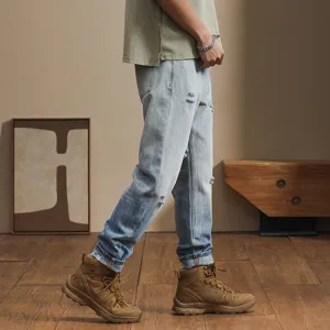 Side detail view of men's loose ripped gradient denim jeans with casual style and boots.