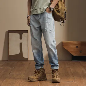 Detail view of men's light blue distressed gradient loose harem jeans featuring casual style.