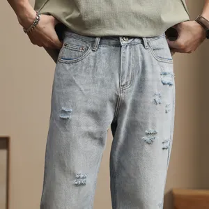 Detail view of men's light wash distressed casual denim jeans with casual loose fit style.