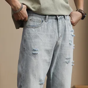 Men's light wash distressed tapered denim jeans, casual loose streetwear style detail view.