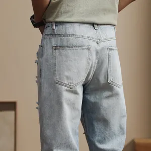 Back detail view of men's loose ripped light blue denim jeans with classic pocket design.