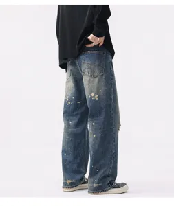 Detail view of men's vintage washed blue wide leg denim jeans with paint splatter and distress.