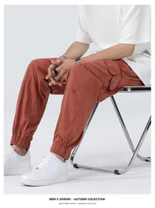 Detailed shot of men's casual rust red cargo pants featuring utility pockets and cuffed hems.