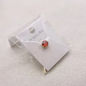 Gedetailleerd detailgezicht van een stijlvolle heren daspin met een rode kristallen steen op kaart.