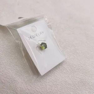 Groene edelsteen stropdas speld broche op witte displaykaart veilig verpakt in zak.