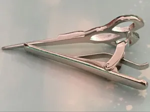 Detailed shot of a silver metal tie clip featuring a unique scissors design, stylish accessory.