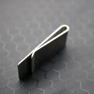 Minimalist stainless steel money clip pocket clip with smooth metallic finish detail.