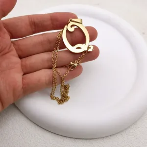 Gold tone stainless steel artistic letter pendant necklace detail view, fashion jewelry.