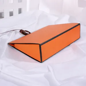 Orange collapsible gift box with brown ribbon, elegant packaging bag for boutique gifts.